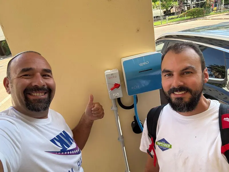 שני גברים מחייכים ליד עמדת טעינה לרכב חשמלי