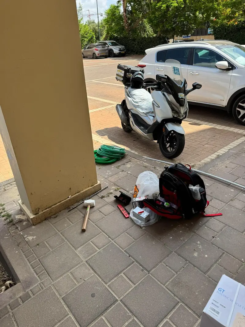 קטנוע ותיק כלים על המדרכה, ליד בניין